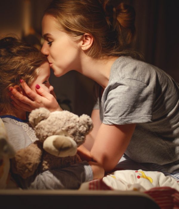 mother puts her daughter to bed and kisses her in the evening